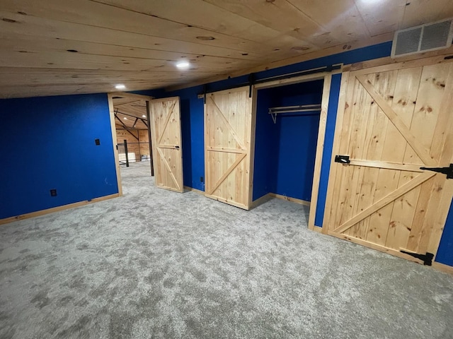 basement with carpet, a barn door, and wood ceiling