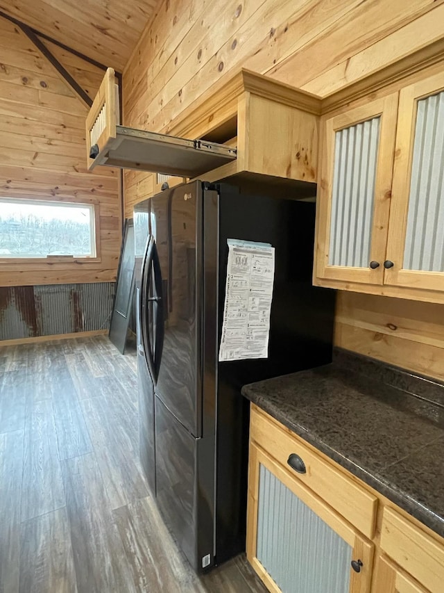 kitchen featuring stainless steel fridge, light brown cabinetry, dark hardwood / wood-style floors, and wood walls