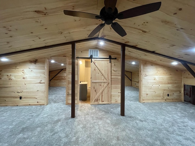 bonus room featuring carpet flooring, vaulted ceiling, ceiling fan, wooden walls, and a barn door