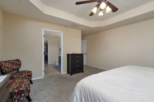 carpeted bedroom with ceiling fan, a raised ceiling, a textured ceiling, and connected bathroom