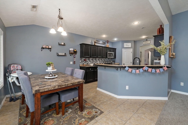 dining area featuring an inviting chandelier, sink, vaulted ceiling, light tile patterned floors, and a textured ceiling