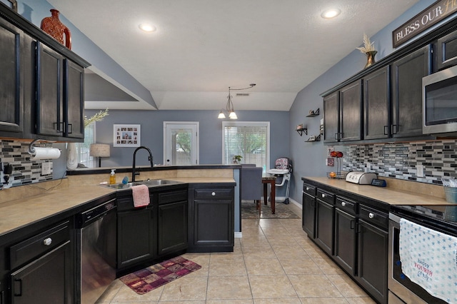 kitchen with sink, pendant lighting, lofted ceiling, decorative backsplash, and appliances with stainless steel finishes