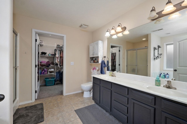 bathroom featuring a textured ceiling, vanity, tile patterned floors, and a shower with door