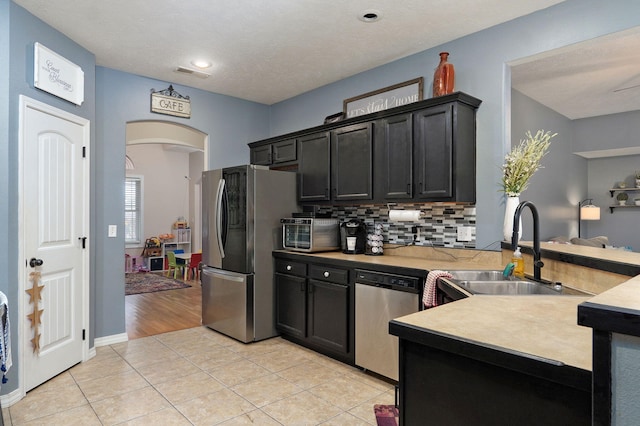 kitchen with light tile patterned flooring, stainless steel appliances, tasteful backsplash, and sink