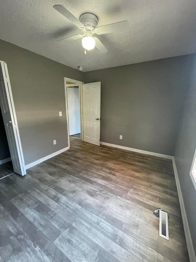 unfurnished bedroom featuring a closet, ceiling fan, dark hardwood / wood-style flooring, and a textured ceiling