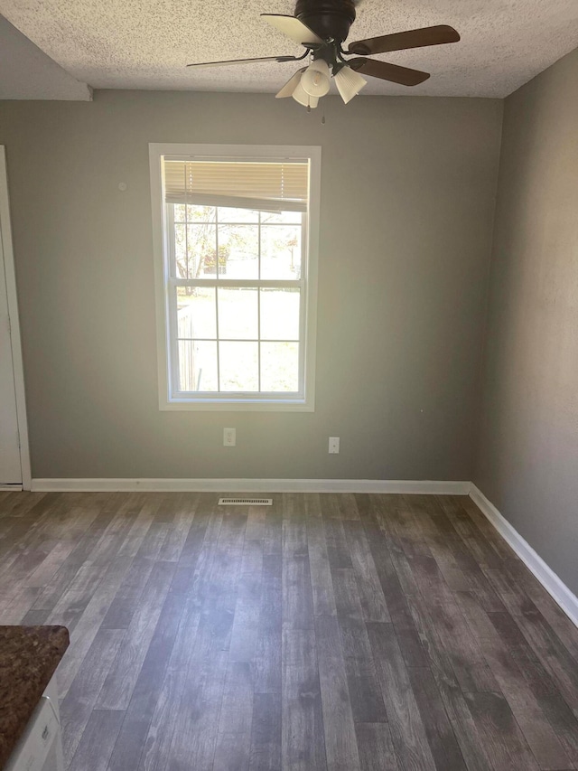 spare room with dark hardwood / wood-style floors, ceiling fan, and a textured ceiling