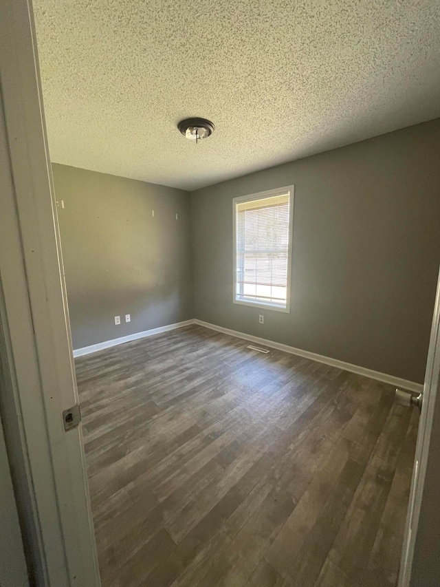 spare room with dark hardwood / wood-style flooring and a textured ceiling