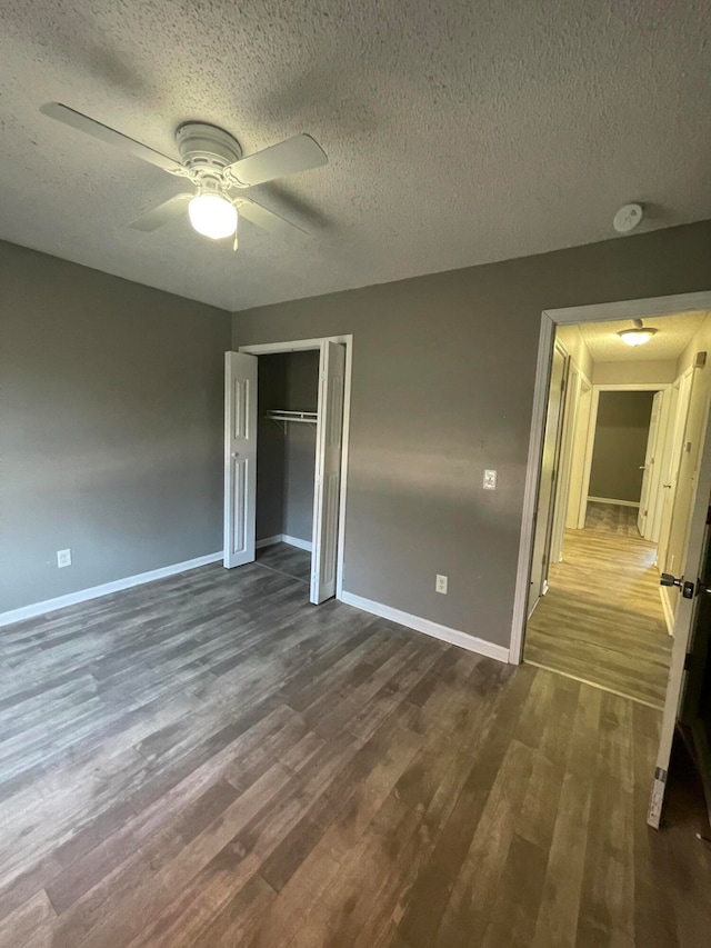 unfurnished bedroom with a textured ceiling, ceiling fan, a closet, and dark hardwood / wood-style floors