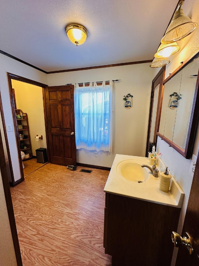 bathroom with vanity, toilet, wood-type flooring, and crown molding