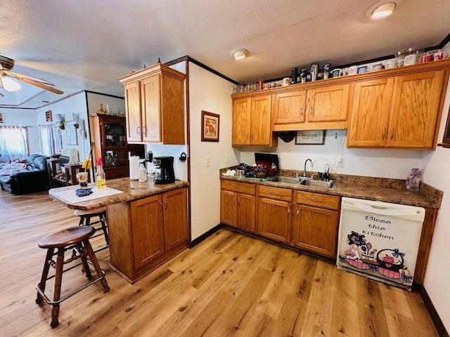 kitchen with a breakfast bar, white dishwasher, sink, light hardwood / wood-style floors, and kitchen peninsula