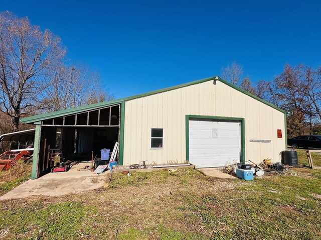 back of house featuring a carport, a garage, and an outbuilding