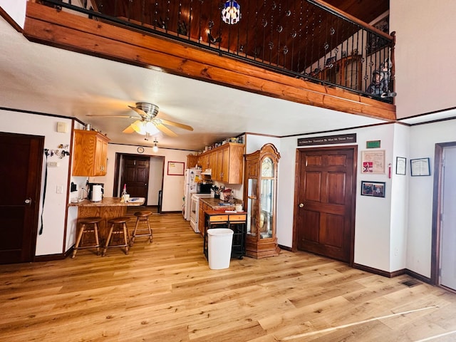 kitchen featuring ceiling fan, a kitchen bar, kitchen peninsula, and light hardwood / wood-style flooring