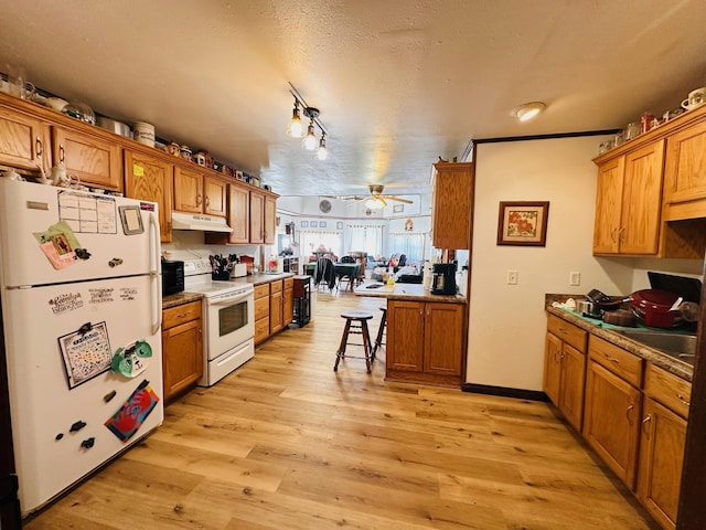 kitchen featuring white appliances, rail lighting, ceiling fan, a textured ceiling, and light hardwood / wood-style floors