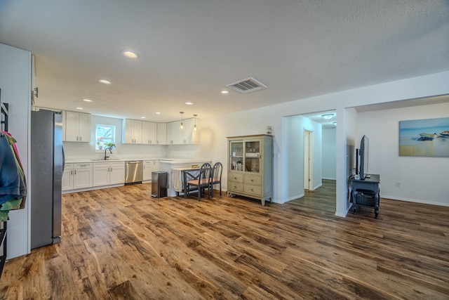 kitchen featuring pendant lighting, sink, dark hardwood / wood-style flooring, white cabinetry, and stainless steel appliances