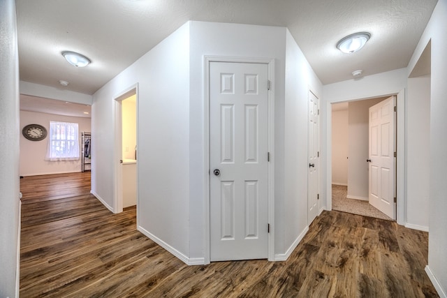 hall featuring a textured ceiling and dark wood-type flooring