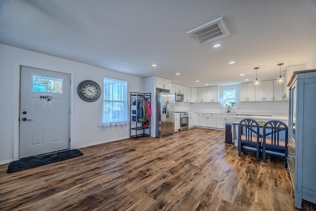 kitchen featuring white cabinets, sink, dark hardwood / wood-style floors, appliances with stainless steel finishes, and decorative light fixtures