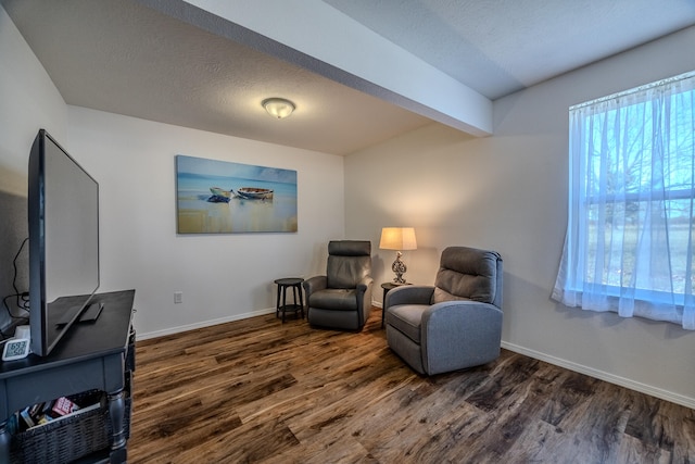 living area featuring beam ceiling, a textured ceiling, and dark hardwood / wood-style floors