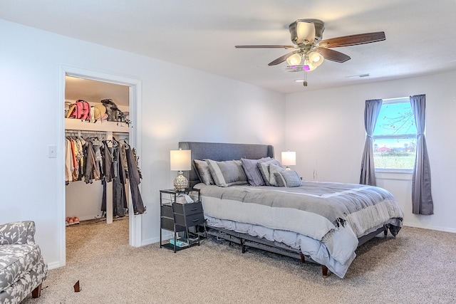 carpeted bedroom with a walk in closet, ceiling fan, and a closet