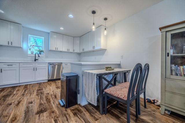 kitchen featuring stainless steel dishwasher, dark wood-type flooring, sink, white cabinets, and hanging light fixtures