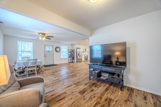 living room with wood-type flooring, plenty of natural light, and ceiling fan