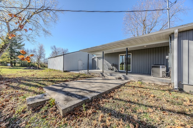 rear view of property with a lawn, an outdoor structure, and central AC unit