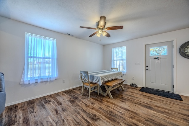 dining space with a textured ceiling, ceiling fan, and dark wood-type flooring