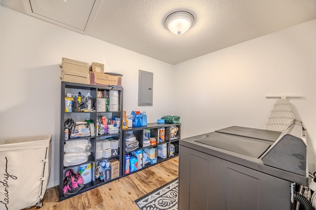 laundry area featuring washing machine and clothes dryer, electric panel, hardwood / wood-style floors, and a textured ceiling