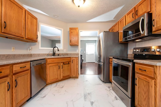 kitchen featuring decorative backsplash, sink, a textured ceiling, and appliances with stainless steel finishes