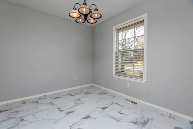 spare room featuring a textured ceiling and a chandelier