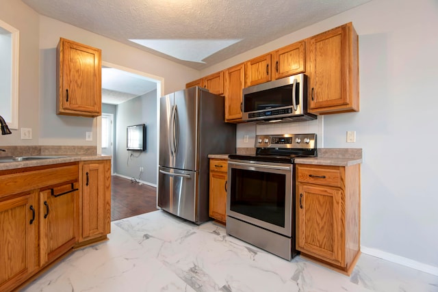 kitchen featuring decorative backsplash, a textured ceiling, stainless steel appliances, and sink