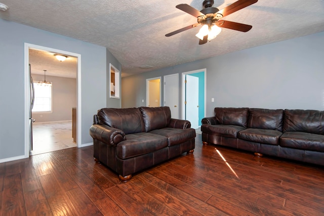 living room with a textured ceiling, ceiling fan, and dark hardwood / wood-style floors