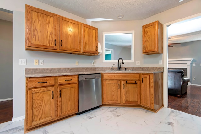 kitchen with a textured ceiling, light hardwood / wood-style floors, stainless steel dishwasher, and sink