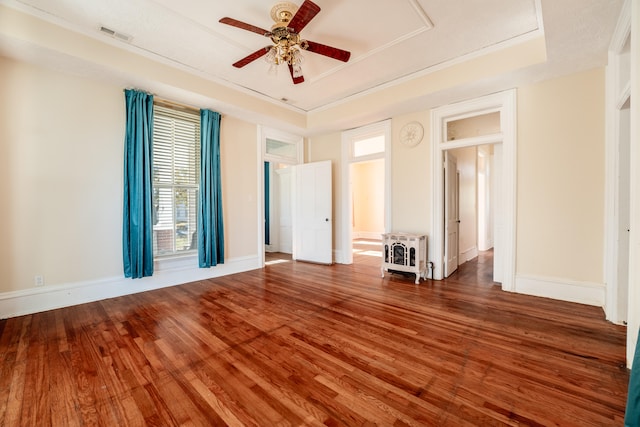 spare room featuring heating unit, hardwood / wood-style flooring, a raised ceiling, and ceiling fan