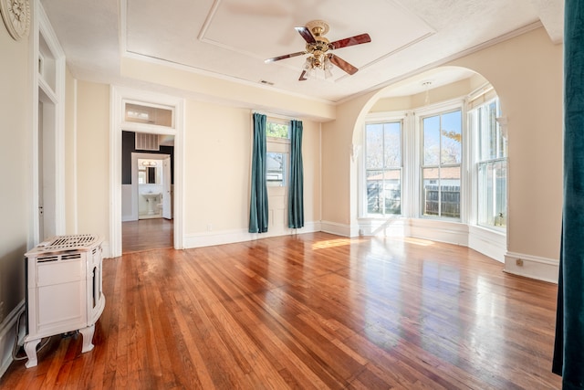 empty room with wood-type flooring, built in features, ceiling fan, and crown molding