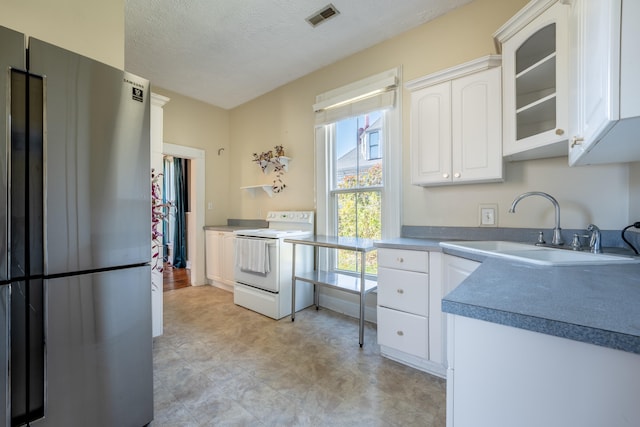 kitchen featuring white cabinetry, stainless steel refrigerator, electric range, and a healthy amount of sunlight