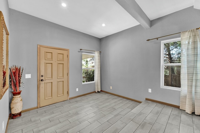 spare room featuring beam ceiling and light wood-type flooring