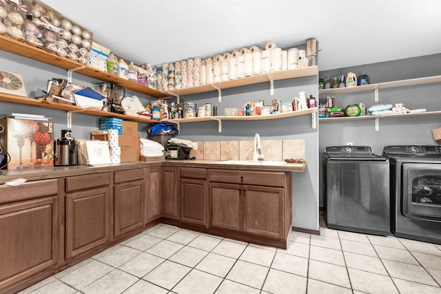 laundry room featuring cabinets, washing machine and dryer, light tile patterned floors, and sink