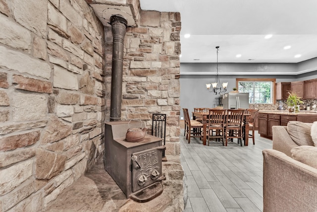 interior space featuring a wood stove, light wood-type flooring, and an inviting chandelier