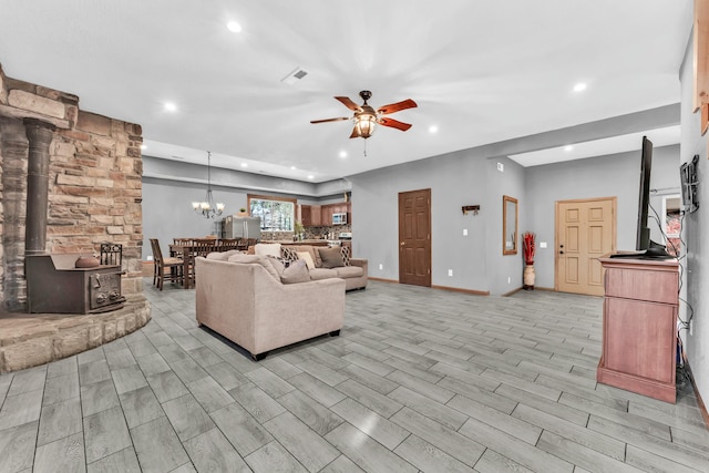 living room with a wood stove, light hardwood / wood-style floors, and ceiling fan with notable chandelier