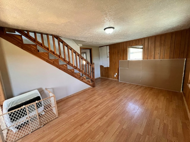 basement featuring a textured ceiling, hardwood / wood-style flooring, and wood walls