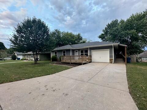 view of front of home featuring a wooden deck, a front lawn, and a garage