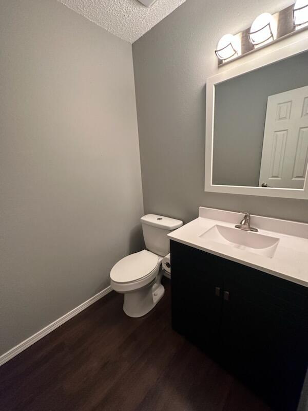 bathroom featuring hardwood / wood-style floors, vanity, toilet, and a textured ceiling