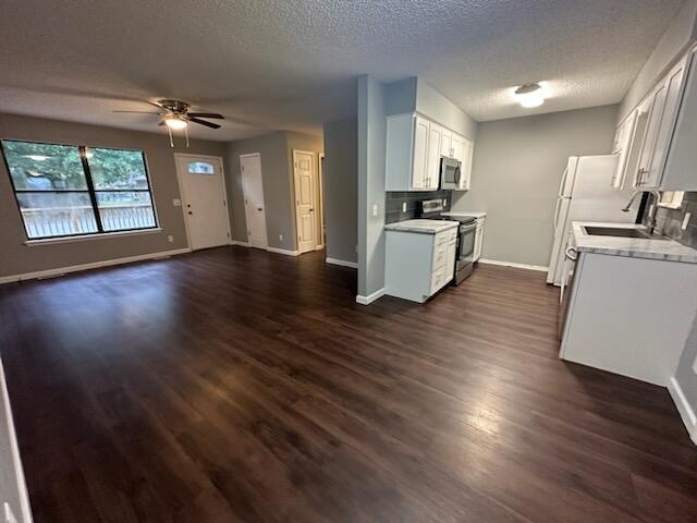 kitchen featuring dark wood-type flooring, ceiling fan, a textured ceiling, white cabinetry, and stainless steel appliances