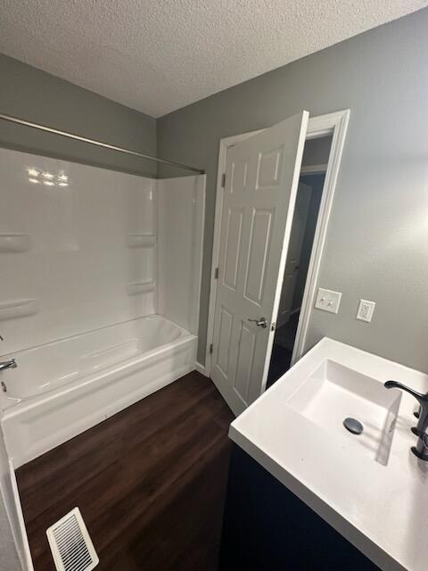 bathroom with shower / tub combination, hardwood / wood-style floors, and a textured ceiling