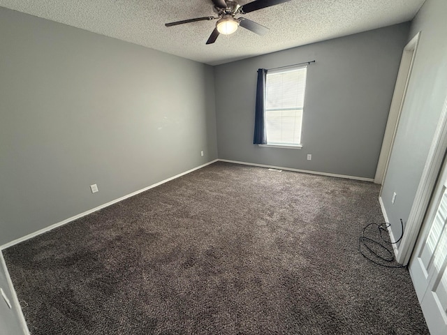 unfurnished room featuring a textured ceiling, dark carpet, and ceiling fan