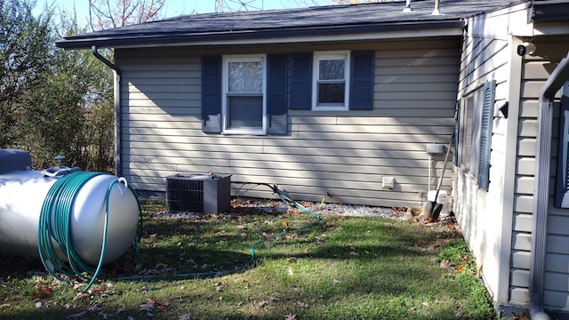 view of side of home with central AC unit and a lawn