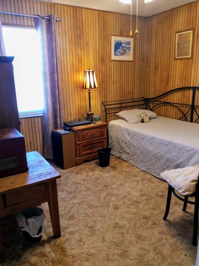 bedroom with carpet flooring and wood walls