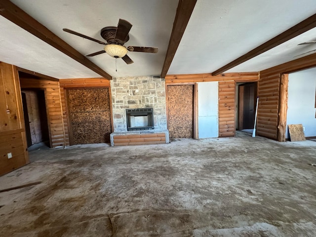 unfurnished living room with beam ceiling, a stone fireplace, and ceiling fan