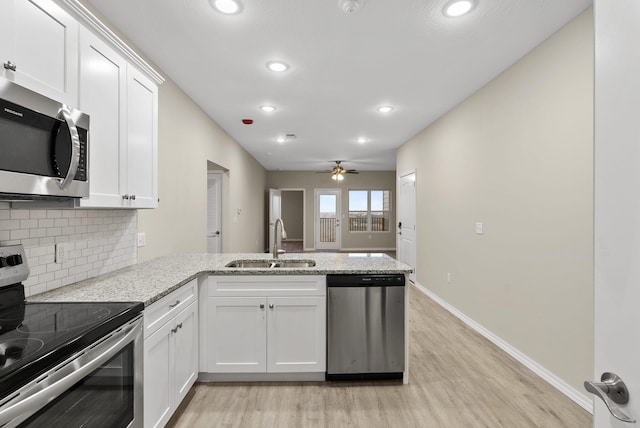 3008 N Vineyards Ter Unit 5, Branson, MO 65616 - kitchen featuring appliances with stainless steel finishes, a sink, a peninsula, light wood-style floors, and decorative backsplash