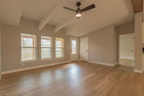 unfurnished living room featuring lofted ceiling with beams, light hardwood / wood-style floors, and ceiling fan